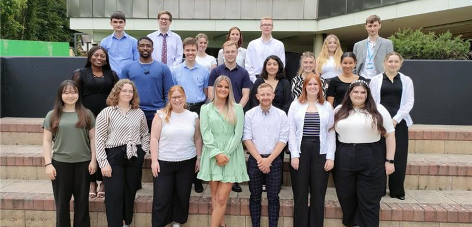 Group of young people standing on the steps of a council building smiling for the camera in a group photograph. 