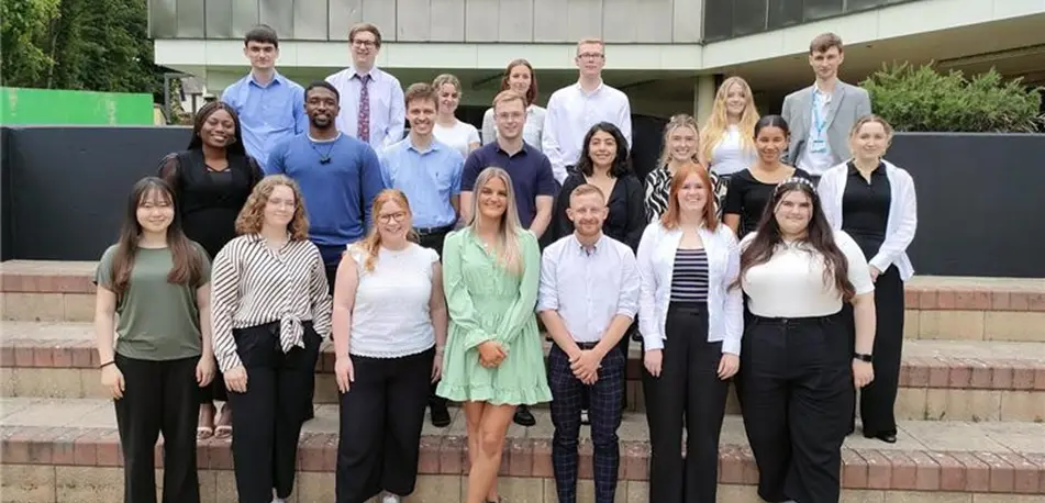Group of young people standing on the steps of a council building smiling for the camera in a group photograph.