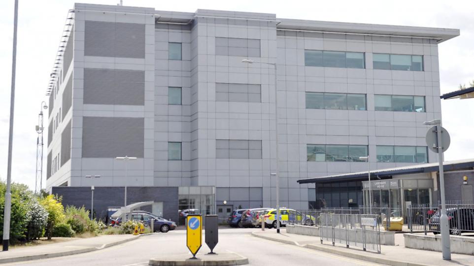 Picture of grey office building with parked cars at the front